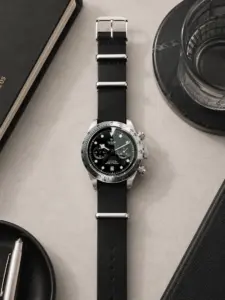 Schwarzes Leder NATO Strap von vild Hamburg an einer Tudor Black Bay Chrono Ref. 79350-0002, stilvoll von oben mit passender Tischdekoration aufgenommen