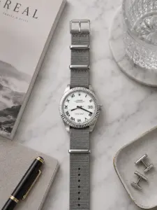 Graues Nylon NATO Strap von vild Hamburg an einer Rolex Datejust 41 Ref. 126334 White Roman, fotografiert von oben auf dekoriertem Tisch mit Accessoires