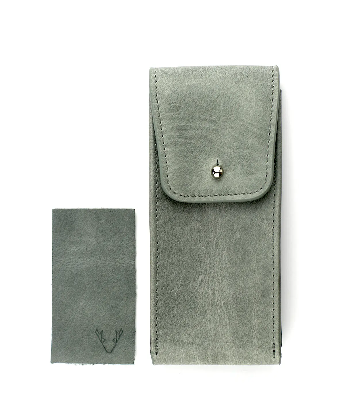 Uhrenetui Leder in Grau mit silbernem Pin Verschluss und Leder Patch daneben liegend auf weißem Hintergrund