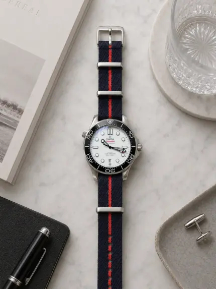 Dunkelblau rot gestreiftes Tudor NATO Strap von vild Hamburg, montiert an einer Omega Seamaster Diver 300M und dekorativ von oben aufgenommen