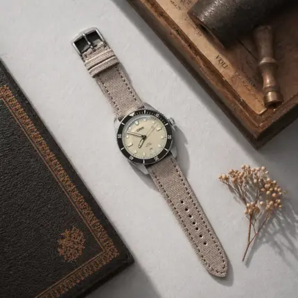 Canvas watch strap, grey beige, by vild Hamburg, mounted on an Oris Divers Sixty-Five and photographed from above with matching decoration.