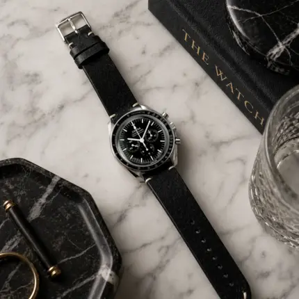 Vintage black leather strap from vild Hamburg, mounted on an Omega Speedmaster Moonwatch and shown decoratively from above.