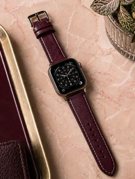 Apple Watch Lederarmband beere von vild Hamburg, montiert an der Uhr auf dekoriertem Marmortisch von oben fotografiert