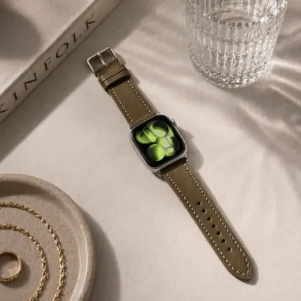 Apple Watch Lederarmband oliv von vild Hamburg, an der Uhr montiert und von oben mit Coffeetable Book Dekoration gezeigt
