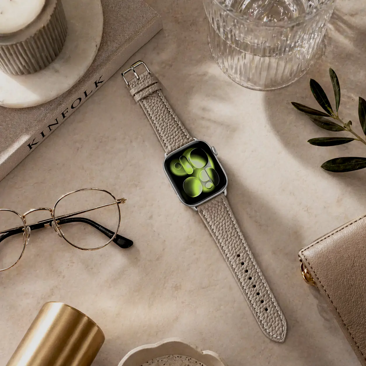 Apple Watch leather strap in taupe by vild Hamburg, mounted on the watch with coffee table book decoration in the top view.