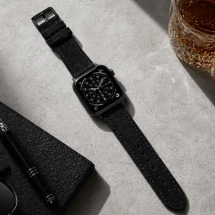 Apple Watch suede strap in black by vild Hamburg, mounted on the watch and shown from above with matching decoration.