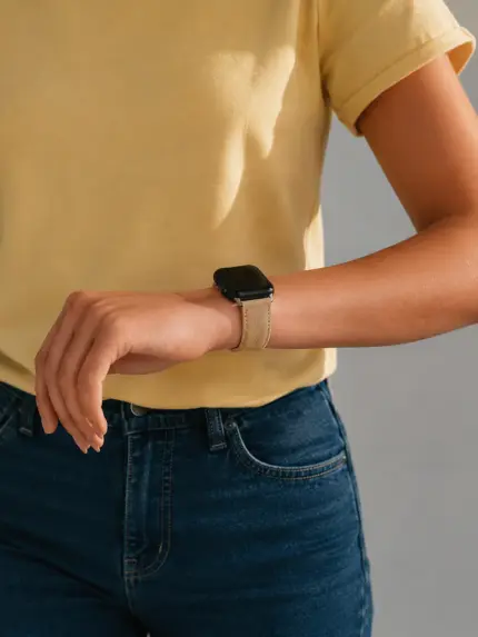 Frau in gelbem T-Shirt und blauer Jeans. Sie trägt eine schwarze Apple Watch mit beigem Wildlederarmband von vild.