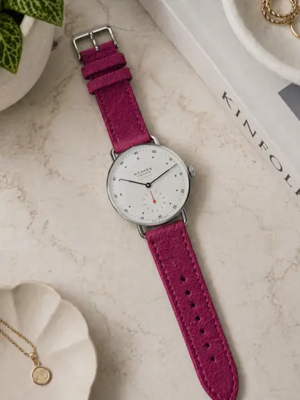 Pink suede bracelet by vild Hamburg, mounted on a NOMOS Metro watch and shown from above with decoration