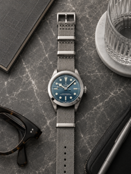 Sterling graues Stoff NATO Strap von vild Hamburg an einer Tudor Black Bay 39 Ref. 79660-0002, von oben mit stilvoller Tischdekoration fotografiert