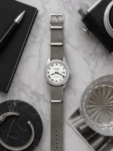Sterling graues Leder NATO Strap von vild Hamburg an einer Rolex Datejust 41 Ref. 126334 White Roman, von oben mit Buch und passender Dekoration aufgenommen