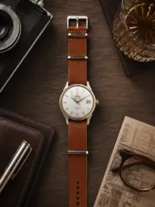 Hellbraunes Leder NATO Strap von vild Hamburg an einer Omega Constellation Vintage Ref. 168.004, fotografiert von oben auf einem dekorierten Tisch