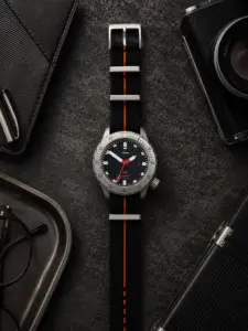 Scuba NATO Strap schwarz orange von vild Hamburg, an einer Sinn U1 montiert und von oben auf dekoriertem Tisch fotografiert