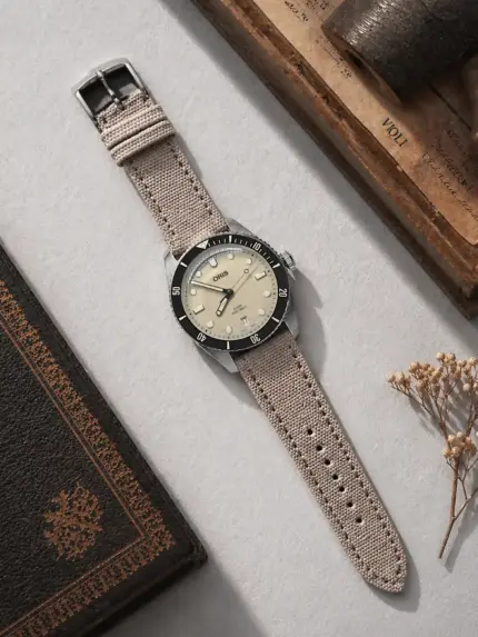 Canvas watch strap, grey beige, by vild Hamburg, mounted on an Oris Divers Sixty-Five and photographed from above with matching decoration.