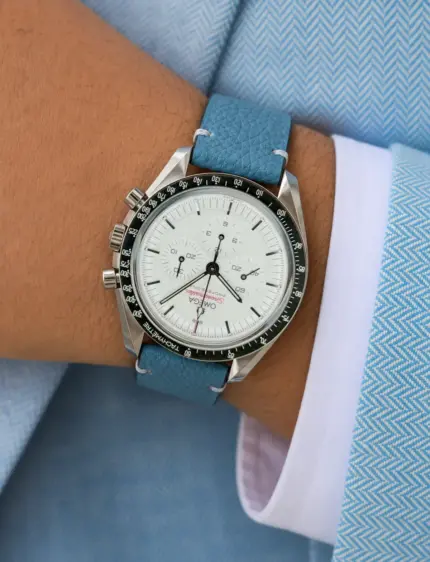 Vintage blue leather watch strap from vild Hamburg on a white Omega Speedmaster Professional on the wrist of a man wearing a light blue jacket and white shirt