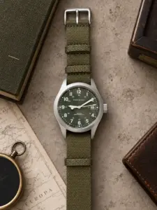 Textile NATO strap SIERRA in olive by vild, mounted on a Hamilton Khaki and shown from above with matching table decoration