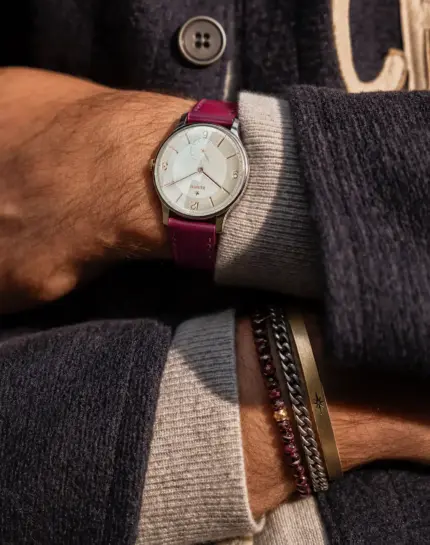 Leather watch strap in raspberry by vild Hamburg, worn on a vintage Zenith Stellina wrist by a man wearing a dark purple wool jacket.