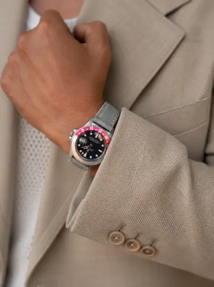 Grey-blue leather watch strap by vild Hamburg on a vintage Rolex GMT-Master Pepsi with faded bezel, worn on the wrist of a woman wearing a beige blazer