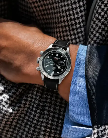 Leather watch strap in black by vild Hamburg, worn on a Tudor Black Bay Chrono ref 79350-0002 on the wrist of a man wearing a black and white jacket.