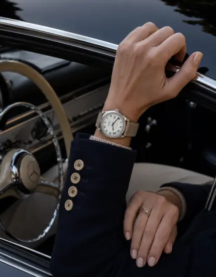 Leder Uhrarmband Taupe von vild Hamburg an einer Rolex datejust 38mm getragen am Handgelenk Frau mit dunkelblauem Blazer, sitzend im Oldtimer Mercedes