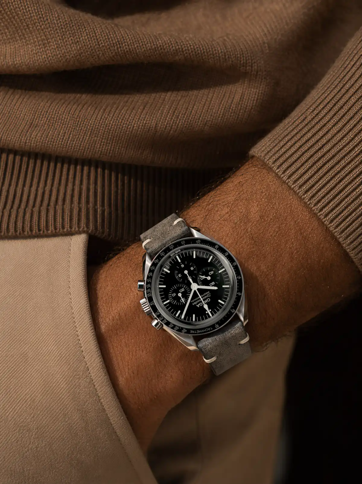 vild-vintage-watch-strap-leather-gray-wrist-omega-speedmaster Vintage dark grey leather watch strap from vild Hamburg, worn on an Omega Speedmaster Professional Moonwatch on the wrist of a man wearing a light brown sweater and light chinos.