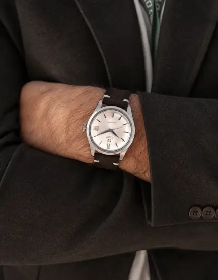 Dark brown suede vintage watch strap from vild Hamburg, worn on the wrist of a man wearing a dark brown jacket.