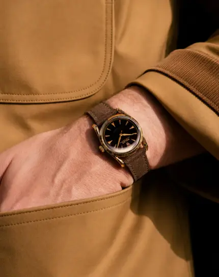 Wildleder Uhrarmband in Dunkelbraun von vild Hamburg an vintage Rolex in Gold am Handgelenk Mann mit Jacke in Gelb-Braun