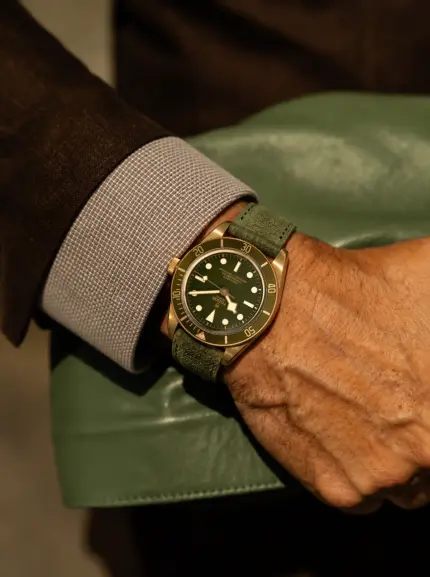 Dark green suede watch strap by vild Hamburg on a Tudor Black Bay Fifty-Eight ref M79018V on the wrist of a man wearing a dark brown jacket and carrying a green leather bag